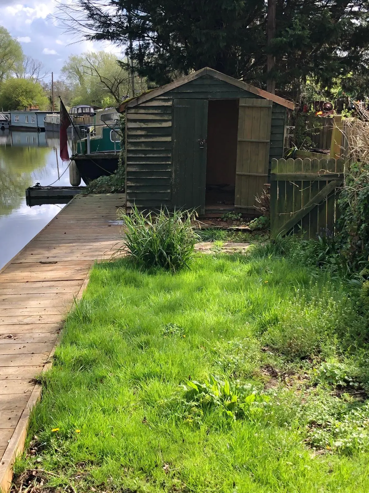 Mooring 33 garden beside the canal, with a timber shed and waterside walkway